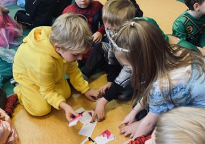 dzieci w strojach karnawałowych układają puzzle