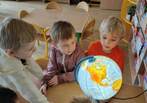 Trzech chłopców patrzy na podświetlany globus