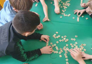 Dzieci bawią się drewnianymi kafelkami z literami i cyfrmi