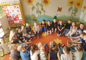 Dzień Kolorowej Skarpetki - dzieci siedzą w kole na dywanie i pokazują kolorowe skarpetki