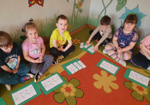 Dzień motyla - dzieci siedzą na dywanie i układają cykl rozwoju motyla