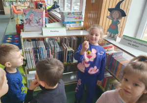 Biblioteka - dzieci szukają ukrytych jajek, dziewczynka trzyma w ręku znalezione jajko