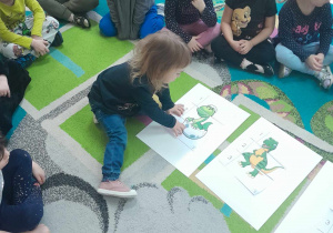 Dziewczynka układa ilustrację dinozaura pociętą na puzzle