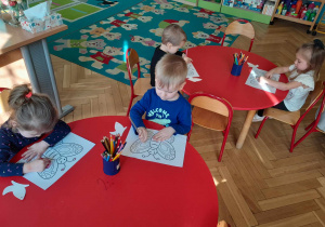 Dzieci kolorują przy stolikach ilustracje motyli