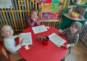 Dzieci kolorują przy stolikach ilustracje motyli