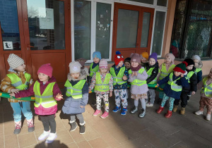 Dzieci pozują do zdjęcia ustawione w rzędzie przed wejściem do biblioteki