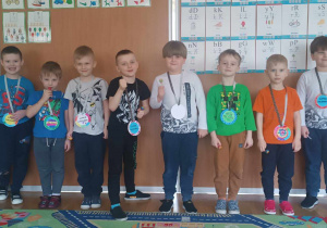 Chłopcy pozują do zdjęcia prezentując medale Super Chłopaka przygotowane dla nich przez dziewczynki