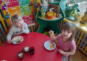 Dwie dziewczynki pozują do zdjęcia ze swoimi talerzykami, na których są świąteczne produkty