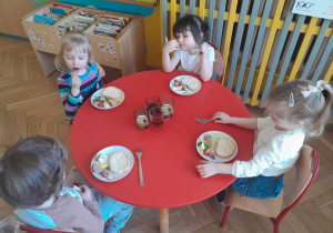 Dzieci pozują przy stoliku ze swoimi talerzykami, na których są świąteczne produkty