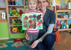 Dziewczynka wraz z mamą prezentuje swój obraz