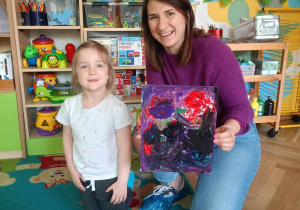 Dziewczynka wraz z mamą prezentuje swój obraz