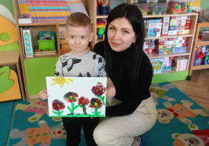 Chłopiec wraz z mamą prezentuje swój obraz