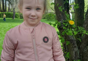 Dziewczynka pozuje do zdjęcia przy drzewie