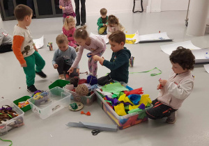 Muzeum Sztuki - dzieci siedzą na podłodze i wybierają z koszy artykuły pasmanteryjne