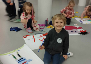 Muzeum Sztuki - dzieci siedzą na podłodze i na kartonach tworzą obrazy z produktów pasmanteryjnych