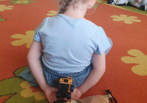 Dzień Świadomości Autyzmu - dziewczynka siedzi tyłem i za pomocą dotyku odgaduje jaki przedmiot ma w rękuu