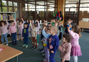 Warsztaty w bibliotece - dzieci podnoszą ręce do góry
