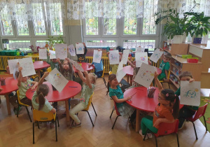 Dzień Ziemi - dzieci siedzą przy stolikach i pokazują swoje wykonane prace