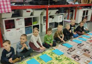 Dzieci siedzące nad niebieskimi kartkami