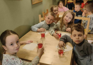 Dzieci siedzące przy stole i pijące sok