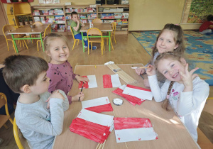 Czworo dzieci przykleja patyczki do flag biało czerwonych