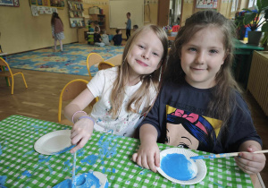 Dwie dziewczynki malują pędzelkami kółeczka na niebieski kolor