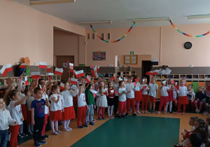 Dzieci ubrane w barwy narodowe śpiewają piosenkę