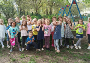 Grupa dzieci pozuje do zdjęcia w ogrodzie przedszkolnym