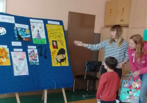 Dwie Pani pokazują wystawę plakatów namalowanych przez dzieci